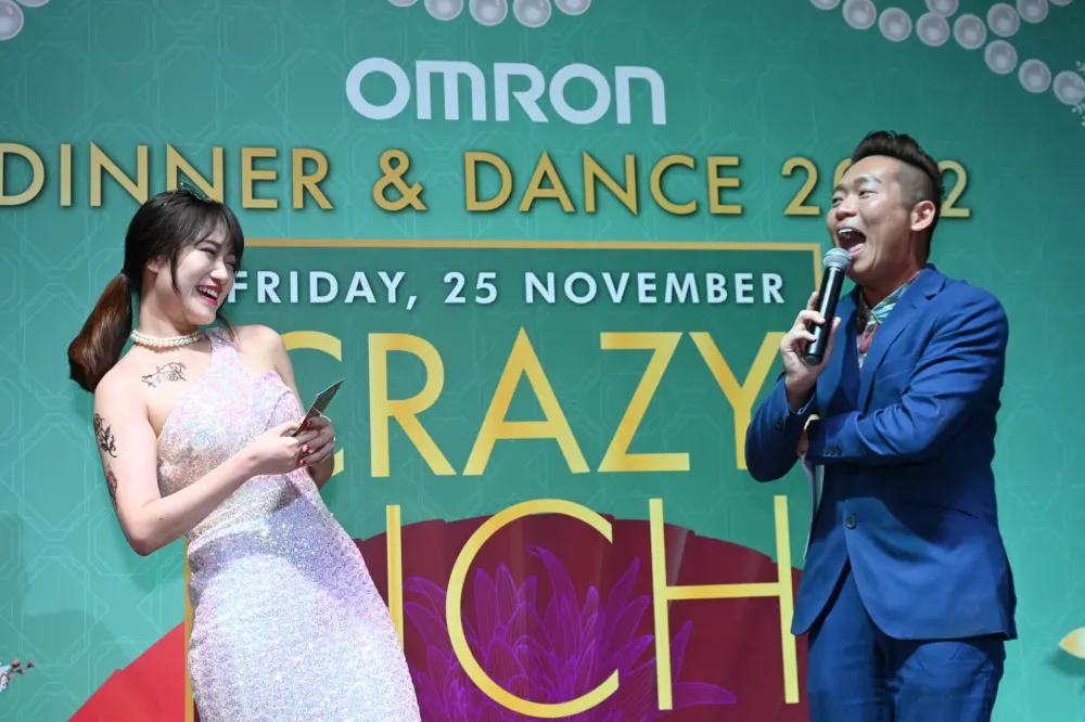 James Yang hosting the Omron Dinner and Dance 2022 beside the event backdrop