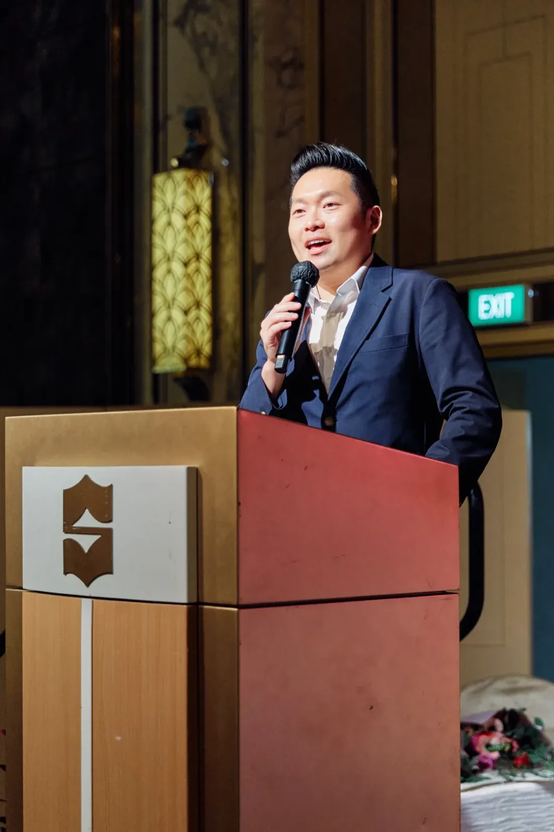 James Yang speaking at a lectern during an event in Singapore